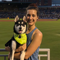 Shannon holds her amazing dog Shuri while standing near an athletic field
