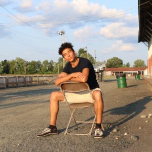 Aahnix poses for a picture on a chair, facing the sunset.