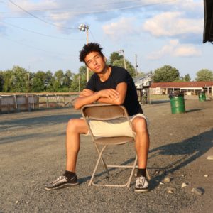 Aahnix poses for a picture on a chair, facing the sunset.