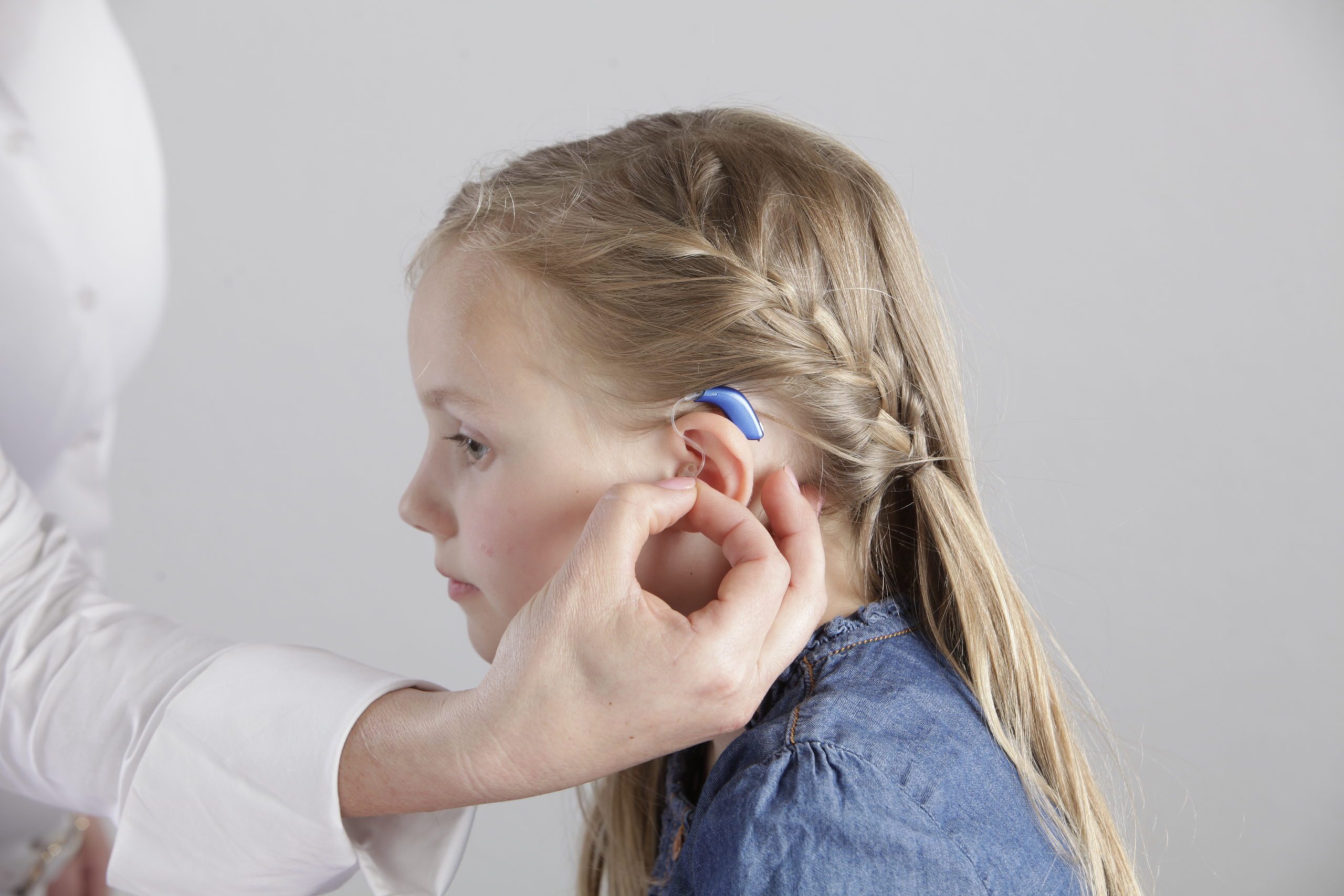 A young girl gets her hearing aid adjusted