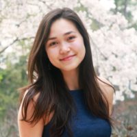 Jessica stands in front of a flowering tree/