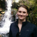 Charlotte smiles in front of a small waterfall
