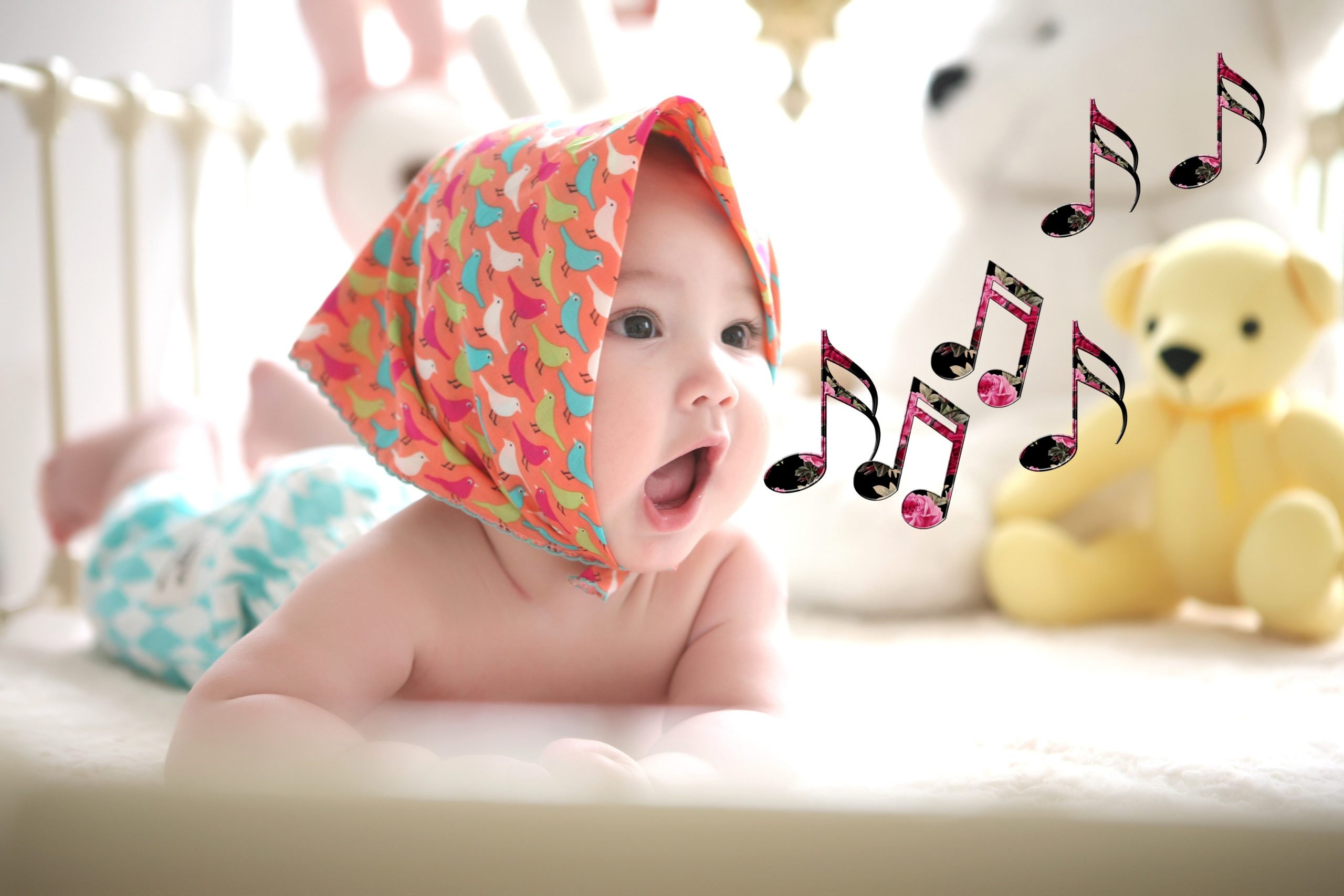 a baby lays with head lifted and notes emanating from her mouth.