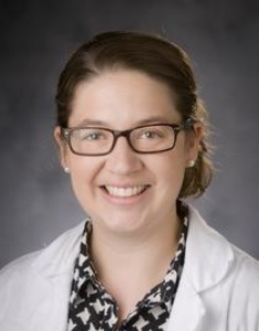 Dr. Elizabeth Erickson smiles and wears a white medical coat in front of a grey background.
